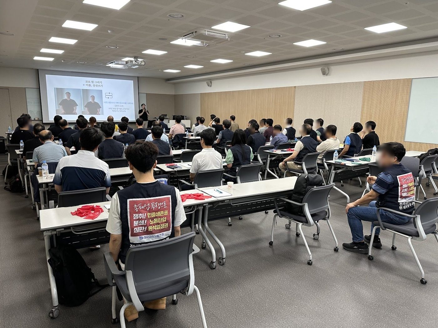 강당에서 임직원들이 두 손을 머리 뒤에 두고 동작을 따라 하는 장면