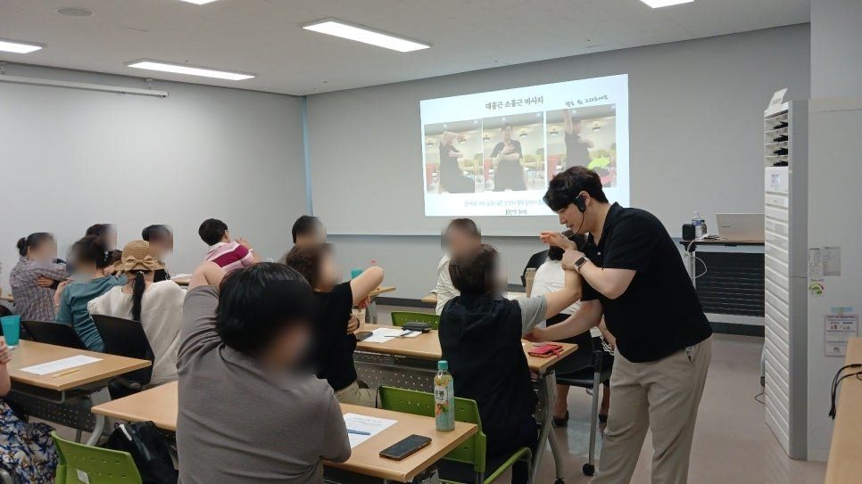 강사가 참가자의 팔을 직접 잡아 동작을 바로잡아 주는 장면