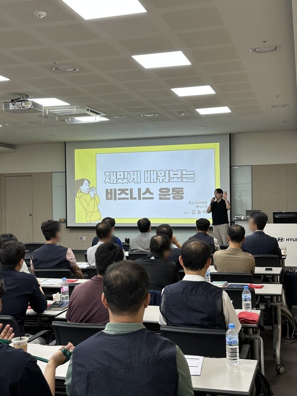 현대자동차 강의실에서 임직원들이 강의를 듣는 뒷모습과 스크린
